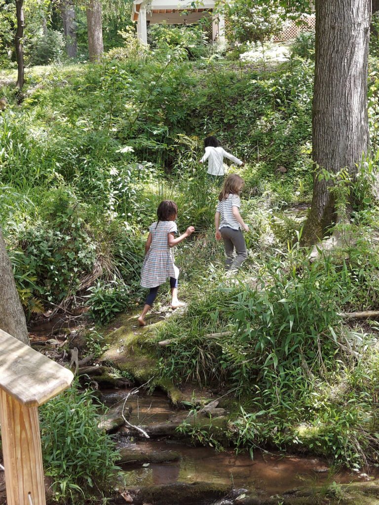 Three children playing on the greenway nature trail, surrounded by greenery and trees. Photo by East Decatur Greenway.