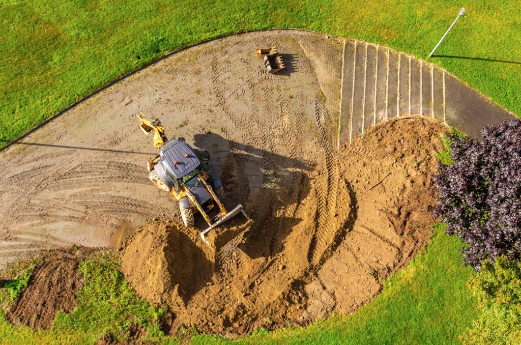An overhead aerial shot of construction and redevelopment work at a brownfield on a sunny day.