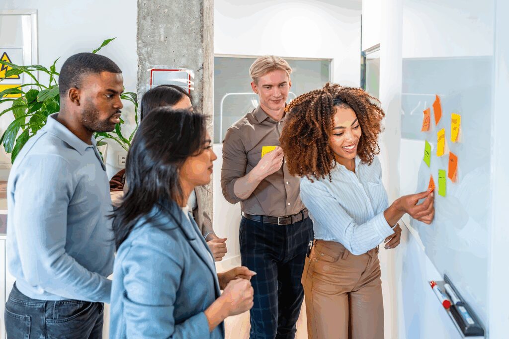 A diverse team working on a white board together.