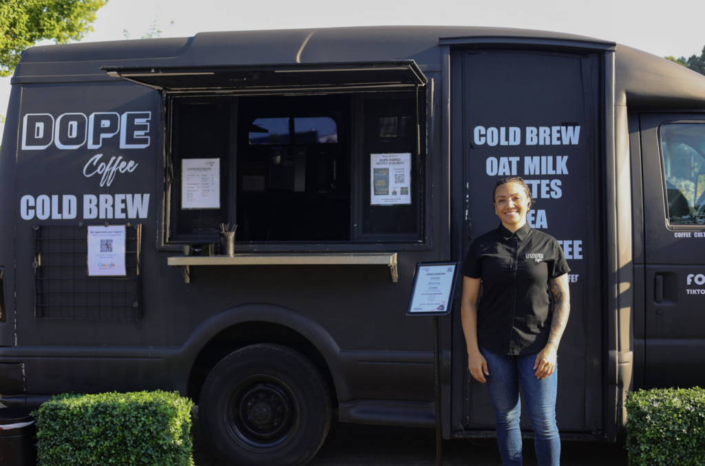 A barista stands outside the Dope Coffee Cold Brew food truck.
